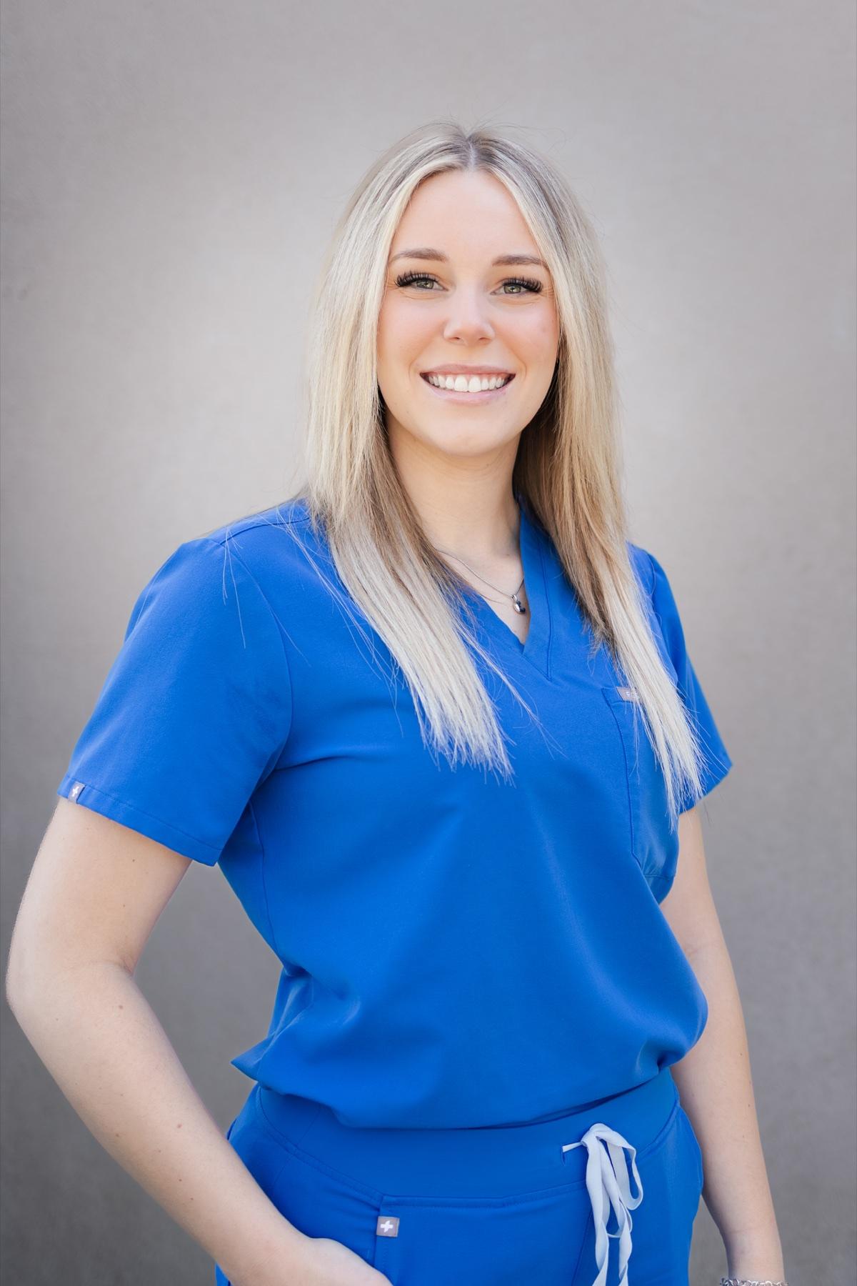 Emilie, Soft Shores dental assistant, smiling in blue scrubs