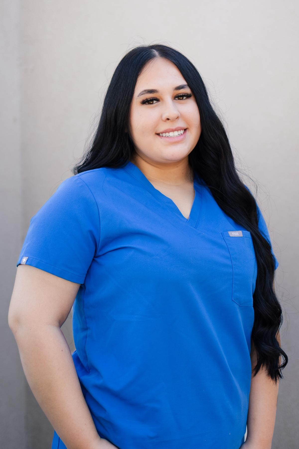 Jaslyn, Soft Shores dental assistant, smiling in blue scrubs