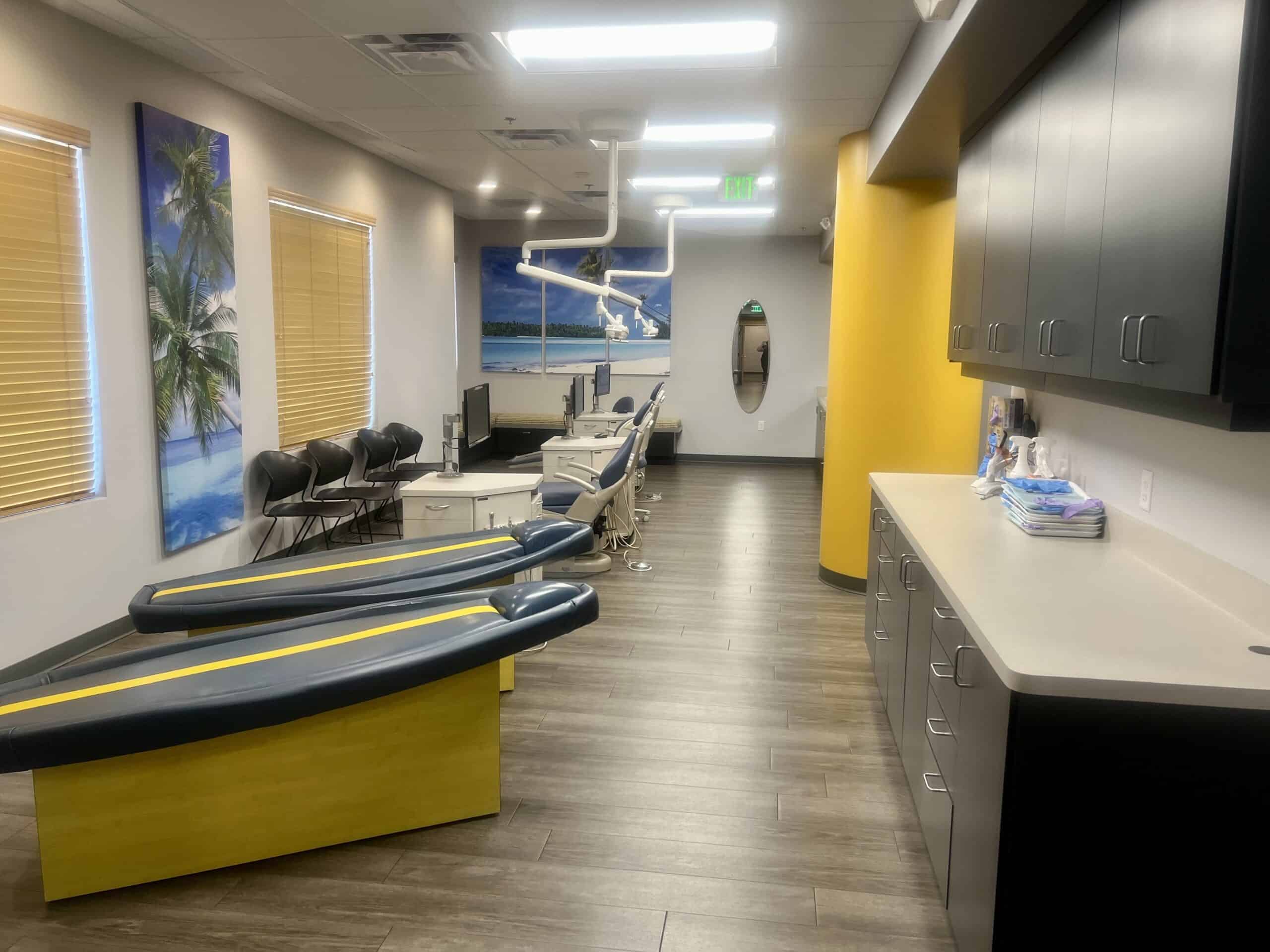 Bright dental clinic with child-friendly decor, dental chairs, and ocean-themed artwork for kids' comfort.